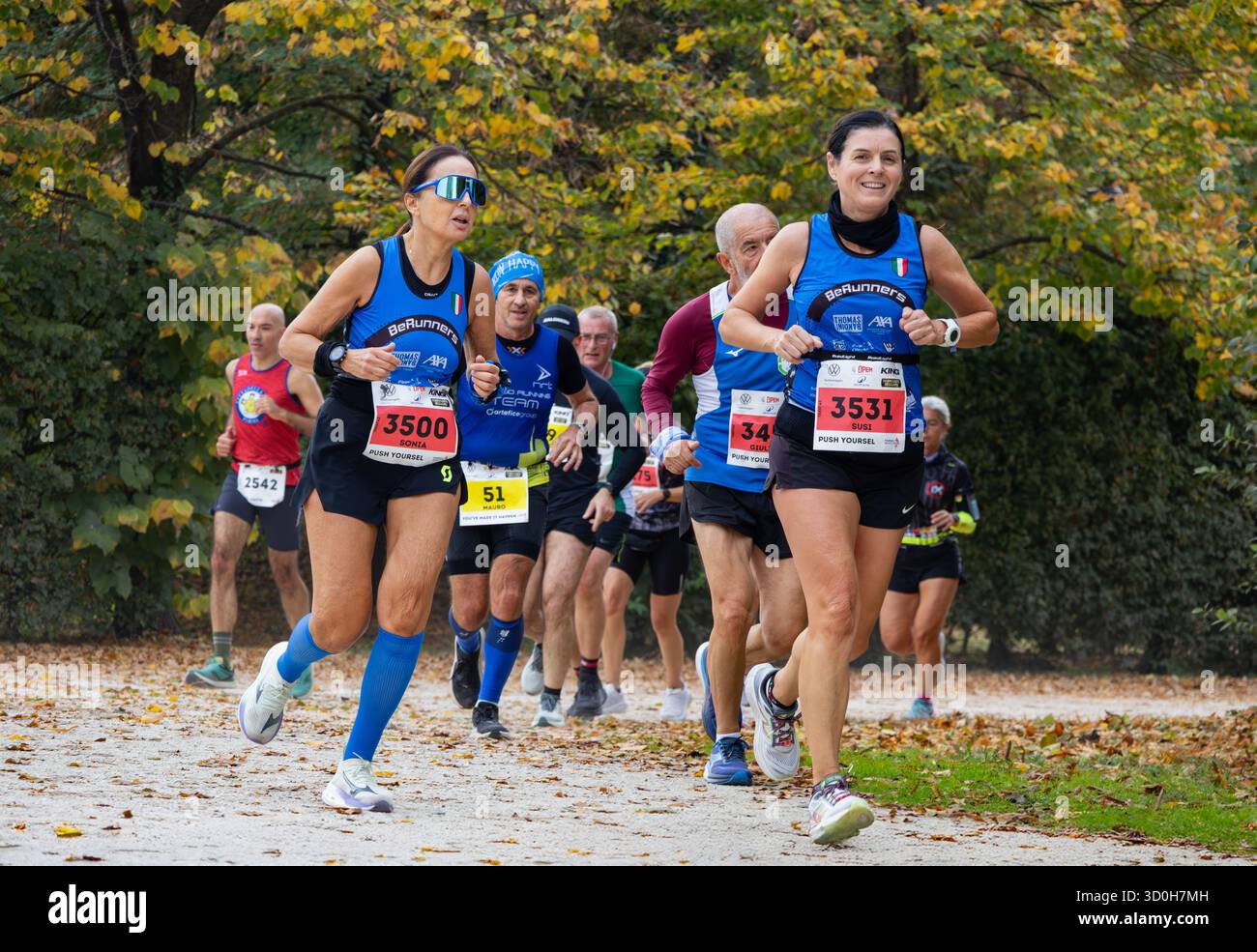 Eine Frau mittleren Alters führt einen Marathon durch den Waldpark und zeigt Kraft, Ausdauer und Entschlossenheit in herbstlicher Atmosphäre Stockfoto