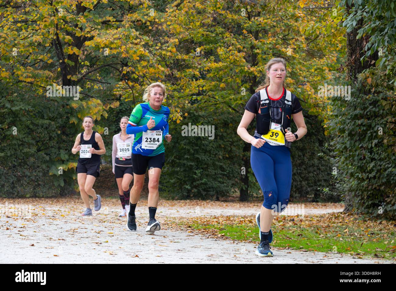 Eine Frau mittleren Alters führt einen Marathon durch den Waldpark und zeigt Kraft, Ausdauer und Entschlossenheit in herbstlicher Atmosphäre Stockfoto