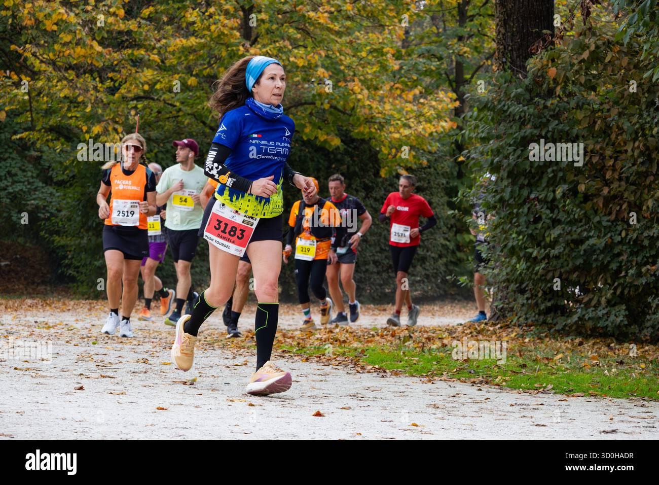 Eine Frau mittleren Alters führt einen Marathon durch den Waldpark und zeigt Kraft, Ausdauer und Entschlossenheit in herbstlicher Atmosphäre Stockfoto
