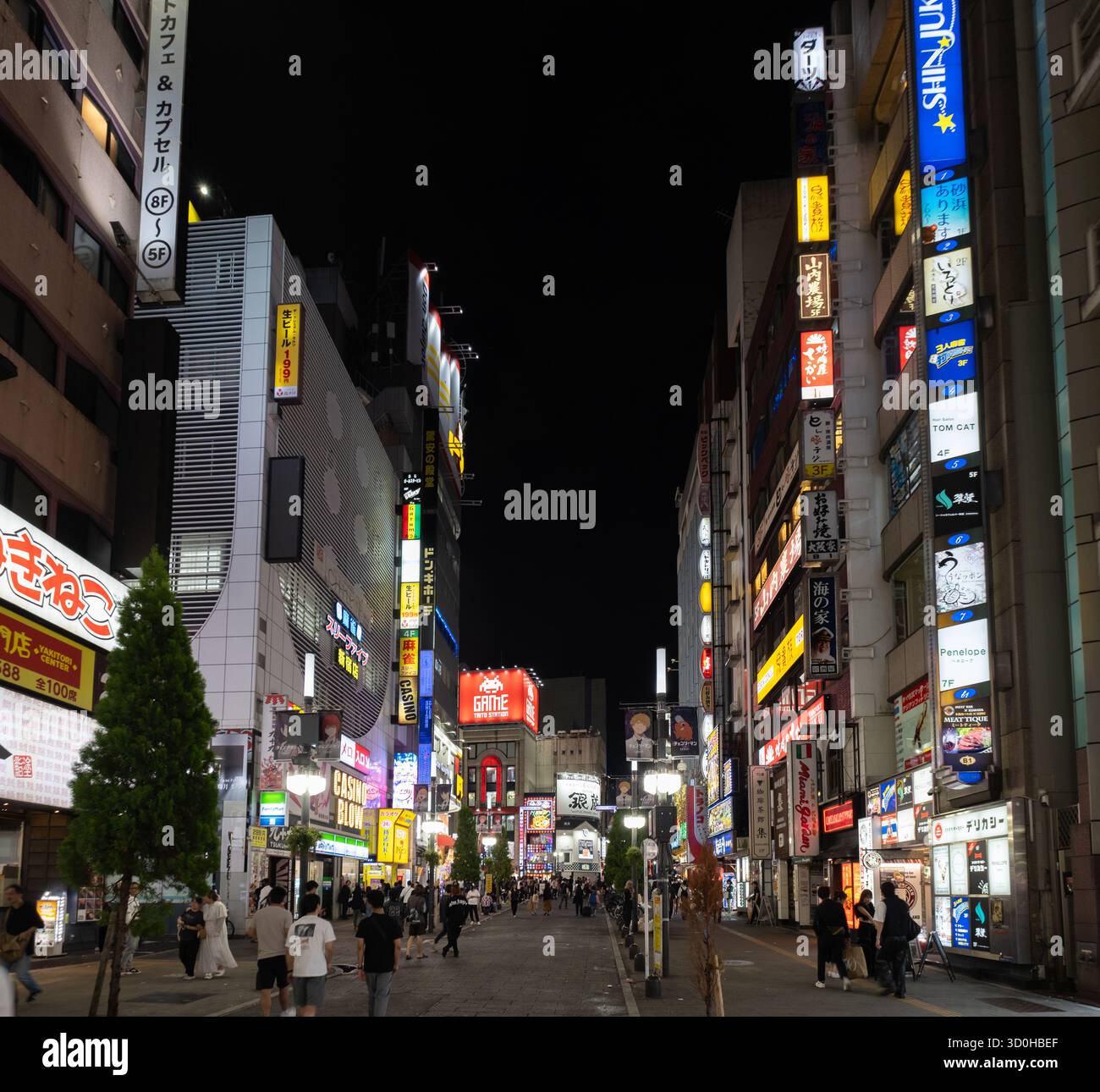 Shinjuku City, Japan - 30. September 2025: Blick auf die lebendige Shinjuku Straße mit Neonschildern, die ein farbenfrohes Leuchten auf die hektische Nachtmenschen werfen. Stockfoto