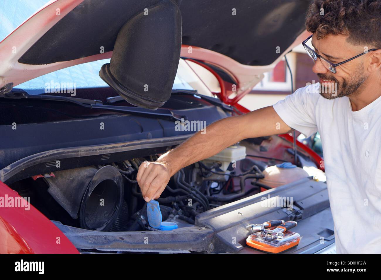 Kfz-Versicherung, Mechaniker, Wartung und Pannen. Mann, der den Flüssigkeitsstand der Scheibenwaschanlage in einem Wohnmobil überprüft, bevor er seinen Urlaub antritt. Stockfoto