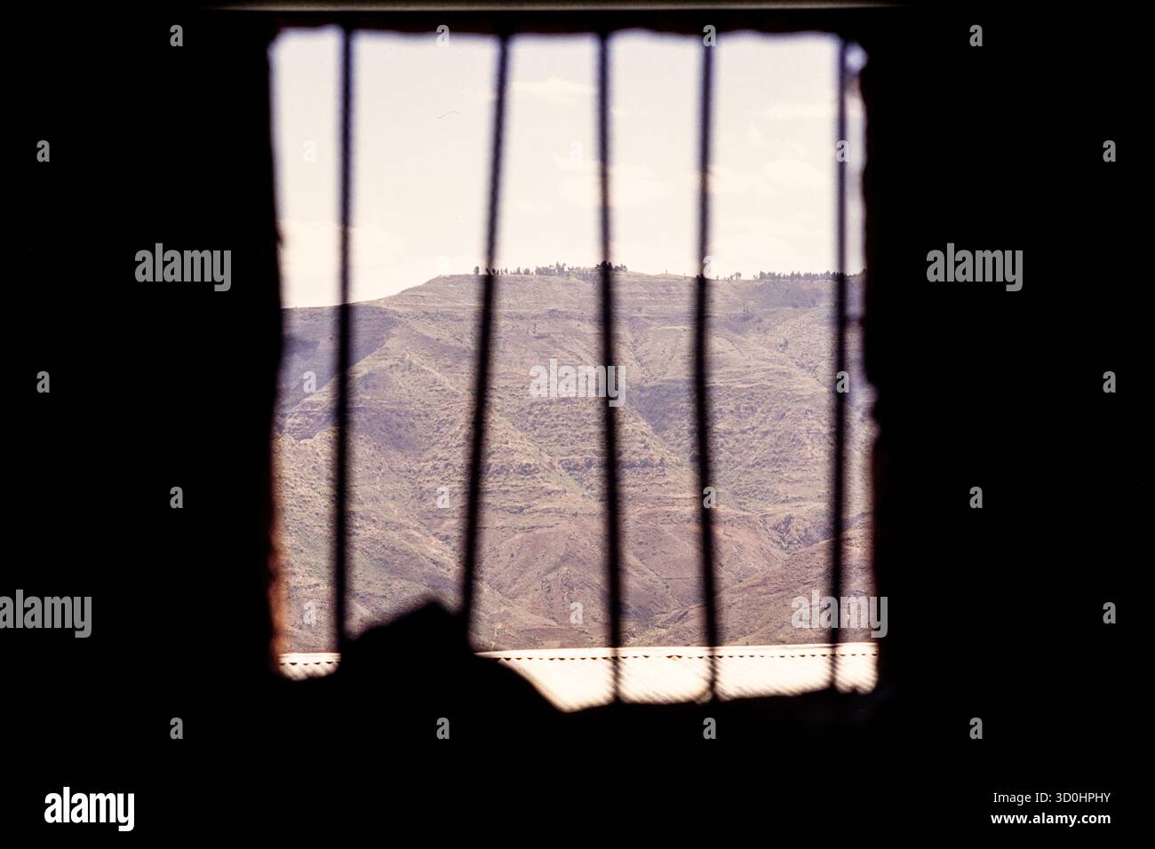 Der Blick auf die Berge durch die Bars eines Fensters von einem einfachen Hotel in Lalibella Nord-Äthiopien. Stockfoto