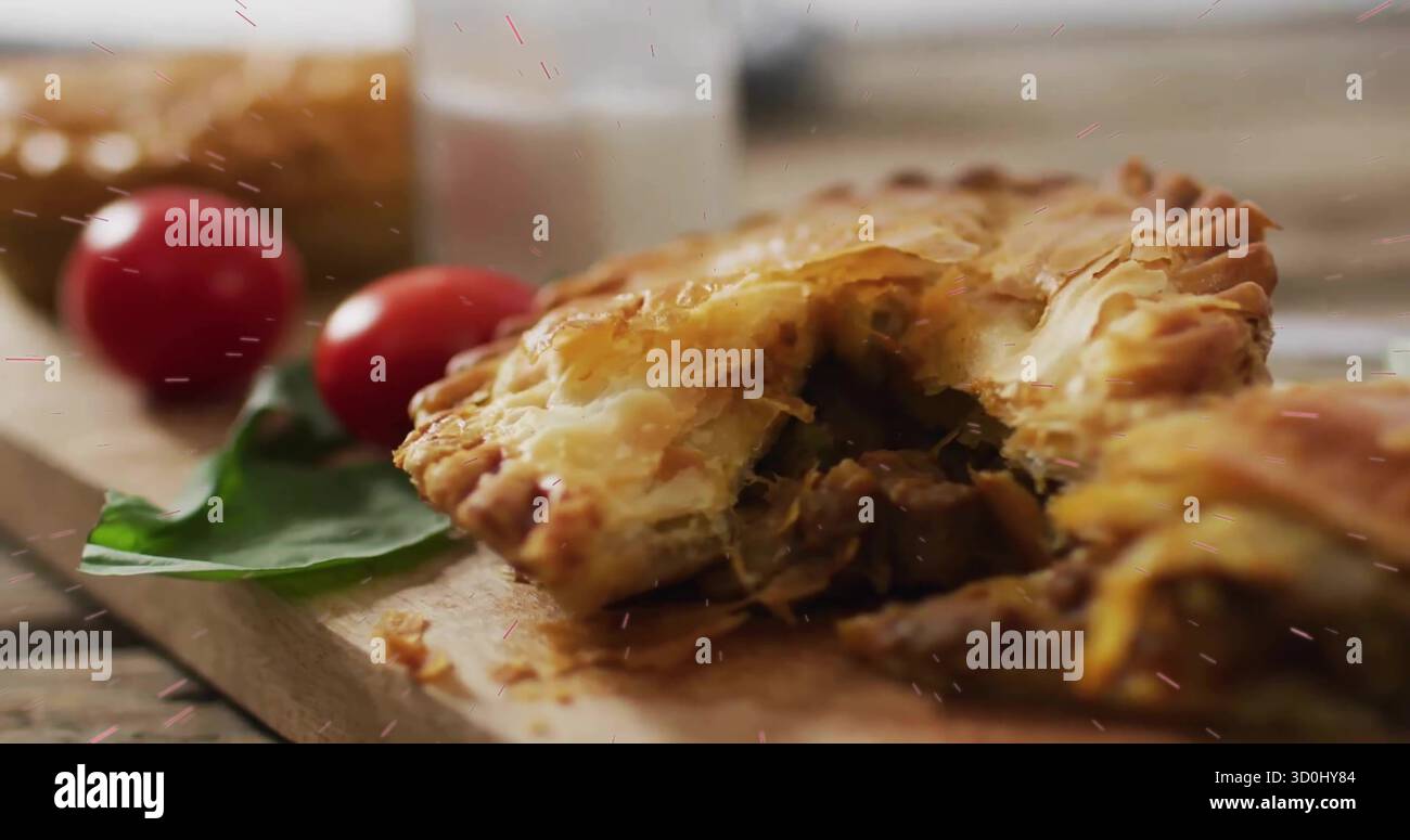 Herzhaftes Gebäck auf hölzernem Schneidebrett in der Küche, mit Kirschtomaten, Basilikum, Glasflasche Stockfoto