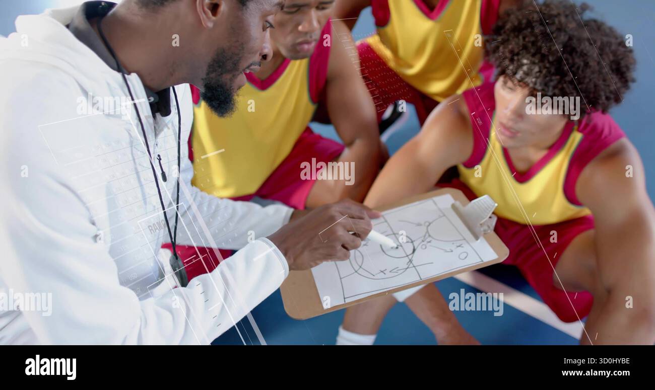 Kniender Trainer hält Clipboard und zeigt auf dem blauen Platz, Spieler aus gelbem Trikot hocken Stockfoto