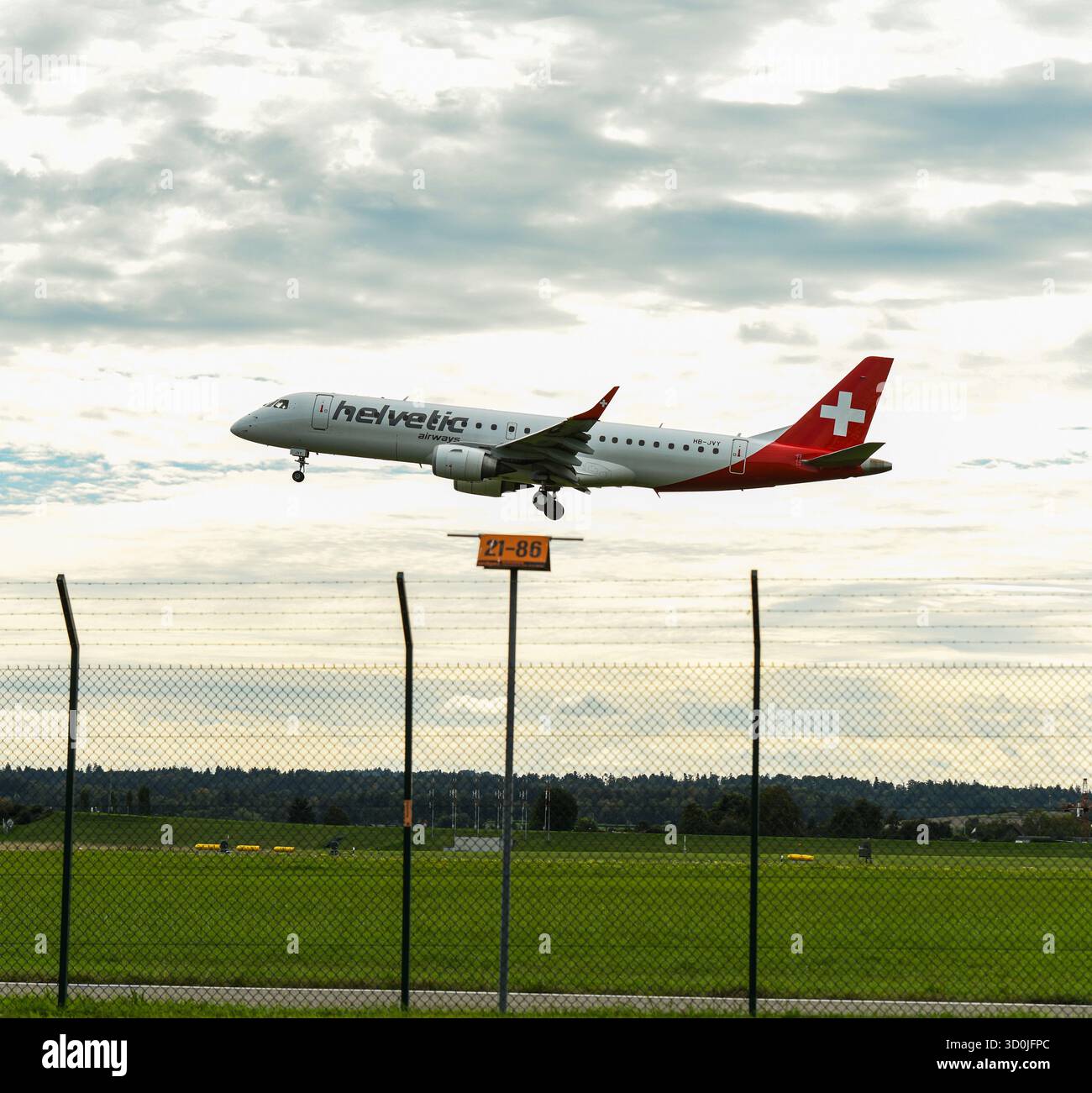 Flugzeuglandung auf der Start- und Landebahn des Flughafens – kommerzieller Jet mit Schweizer Flagge im Flug Stockfoto