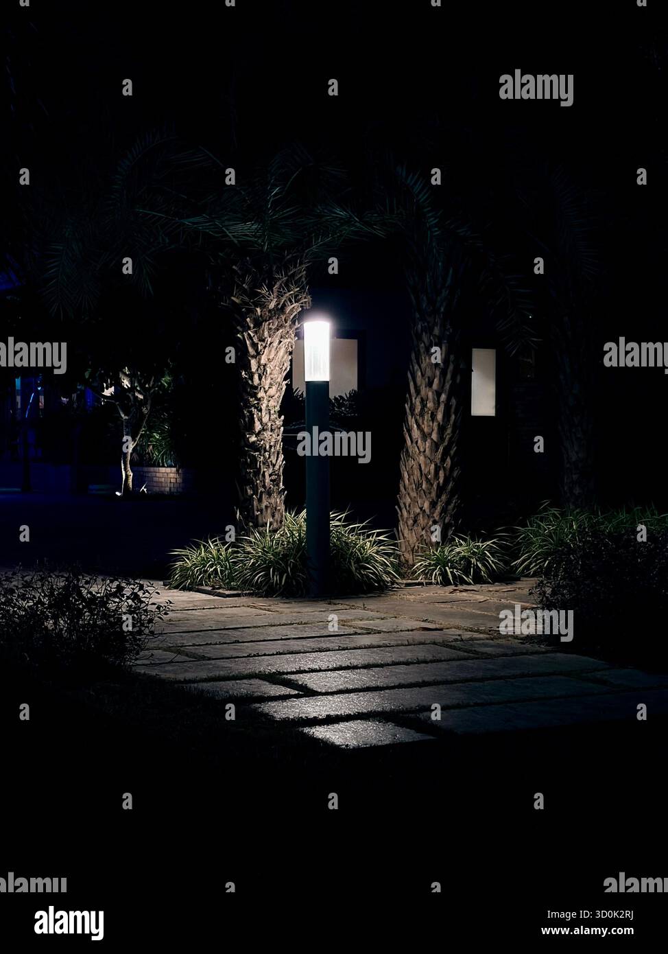 Moderne Gartenlaterne beleuchtet einen Steinweg bei Nacht - Smartphone-aufgenommenes Stockfoto