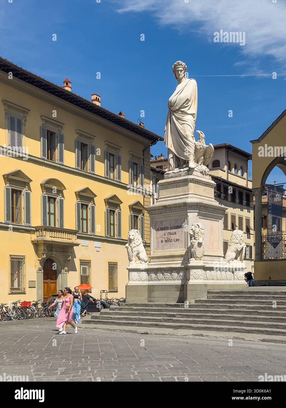 Firenze, Italien, Europa - 14. Juli 2024: Denkmal für Dante Alighieri auf der Piazza di Santa Croce unter blauer Wolkenlandschaft, in der Nähe der Basilika. Menschen und Fahrräder Stockfoto