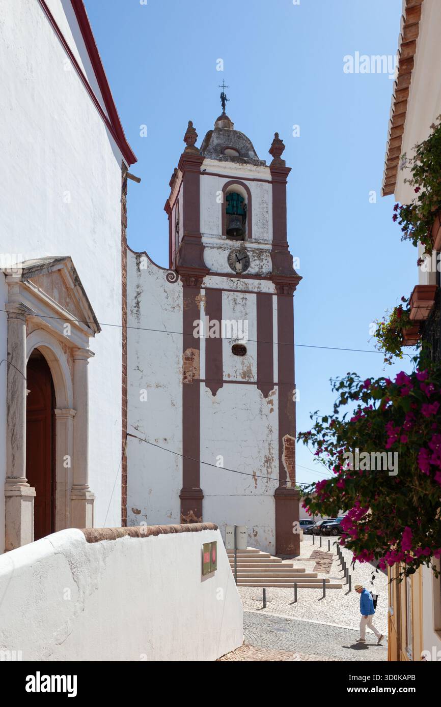 Touristen gehen vorbei am Glockenturm der Kathedrale Sé, einem gotischen Wahrzeichen in der mittelalterlichen Stadt Silves, an der Algarve. Stockfoto