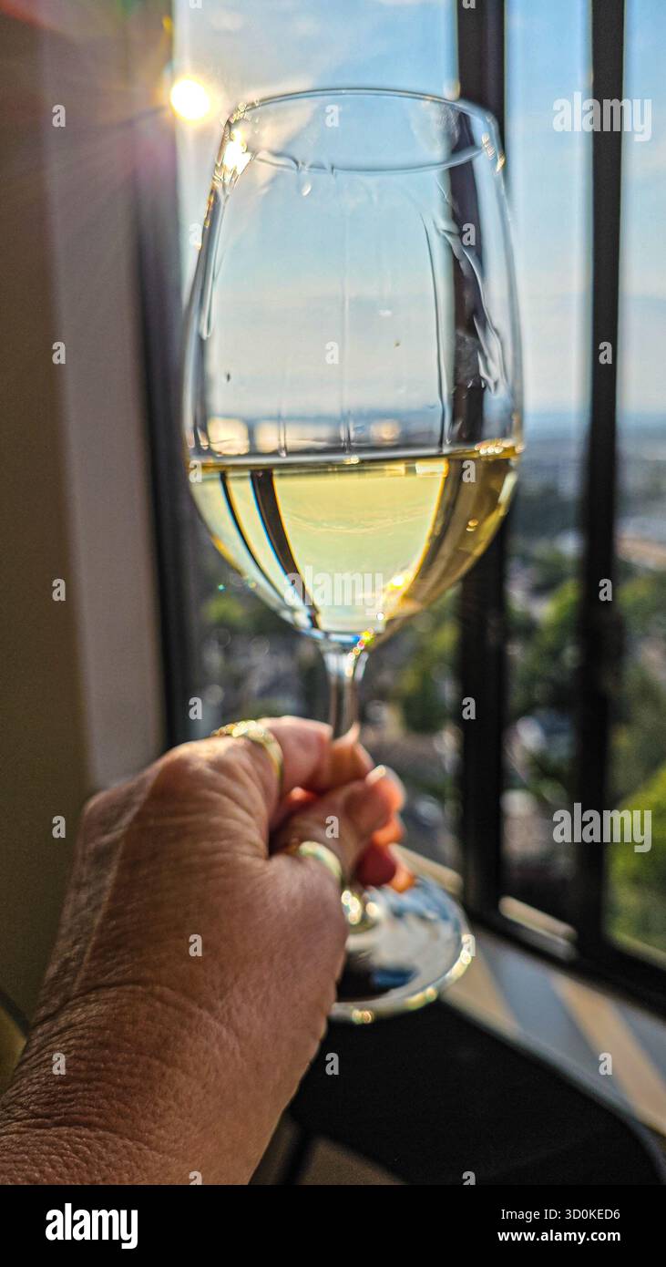 Hand hält ein Glas Weißwein - Smartphone-aufgenommenes Stockfoto
