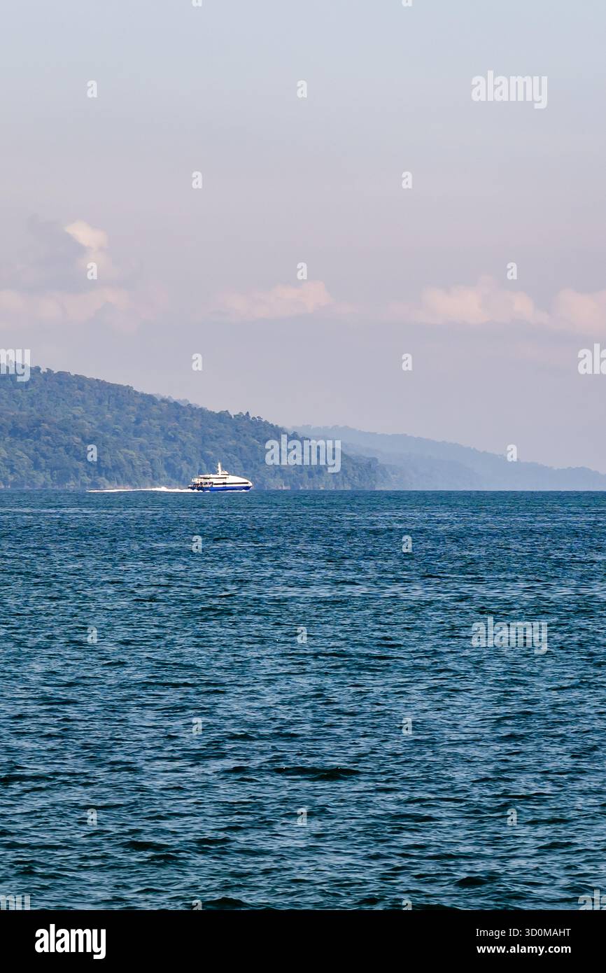 Panoramablick auf das Meer mit weit entfernten bewaldeten Inseln und ruhigem Wasser bei Sonnenaufgang Stockfoto