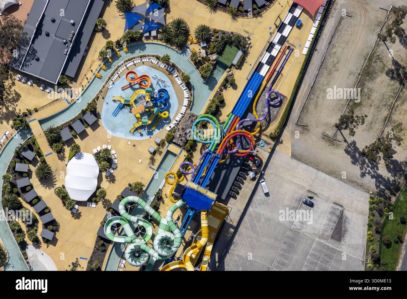 Aus der Vogelperspektive auf den pulsierenden Wasserspielplatz mit verwinkelten Rutschen und faulen Flüssen im Kontrast zur trockenen Landschaft, Tynong North, Victoria, Australien. Stockfoto