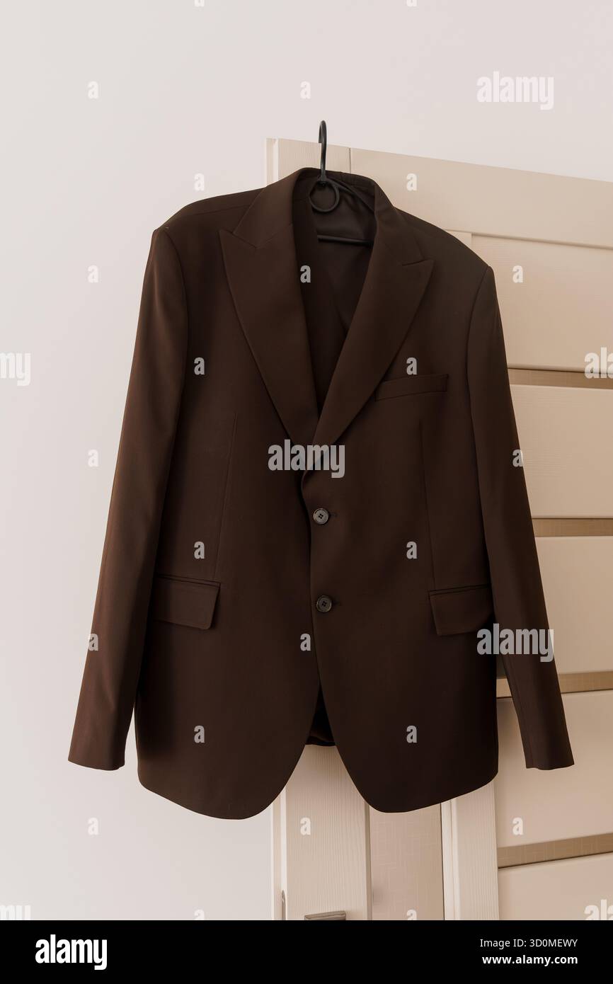 Ein raffinierter brauner Anzug hängt ordentlich an einem schwarzen Kleiderbügel in einem Schrank und stellt professionelle Kleidung, Herrenmode, Modeeinzelhandel und stilvolle B dar Stockfoto