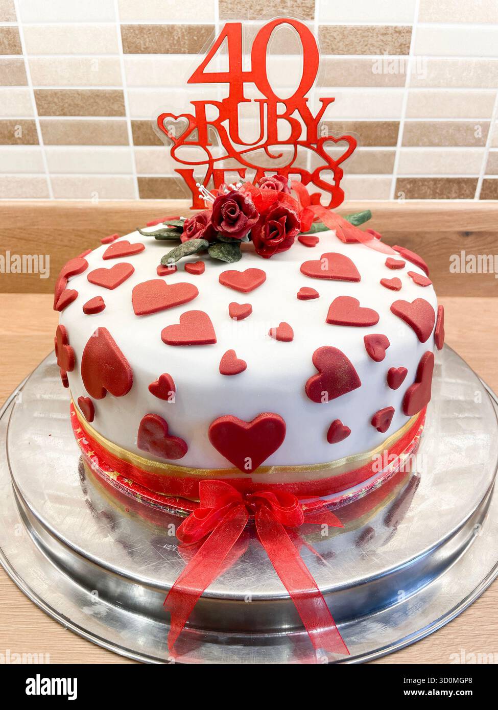 Dekorativer weißer Fondant-Kuchen mit roten Herzen und Rosen für ein 40. Rubinfarbenes Hochzeitstag Stockfoto