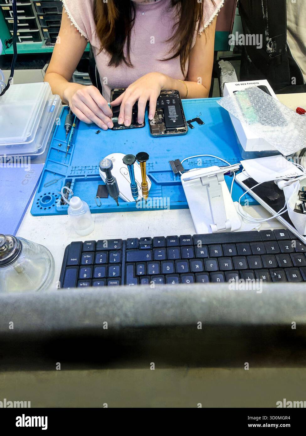 Techniker repariert ein Smartphone mit verschiedenen Werkzeugen auf einer Werkbank in einer Elektronik-Werkstatt in palma mallorca Stockfoto