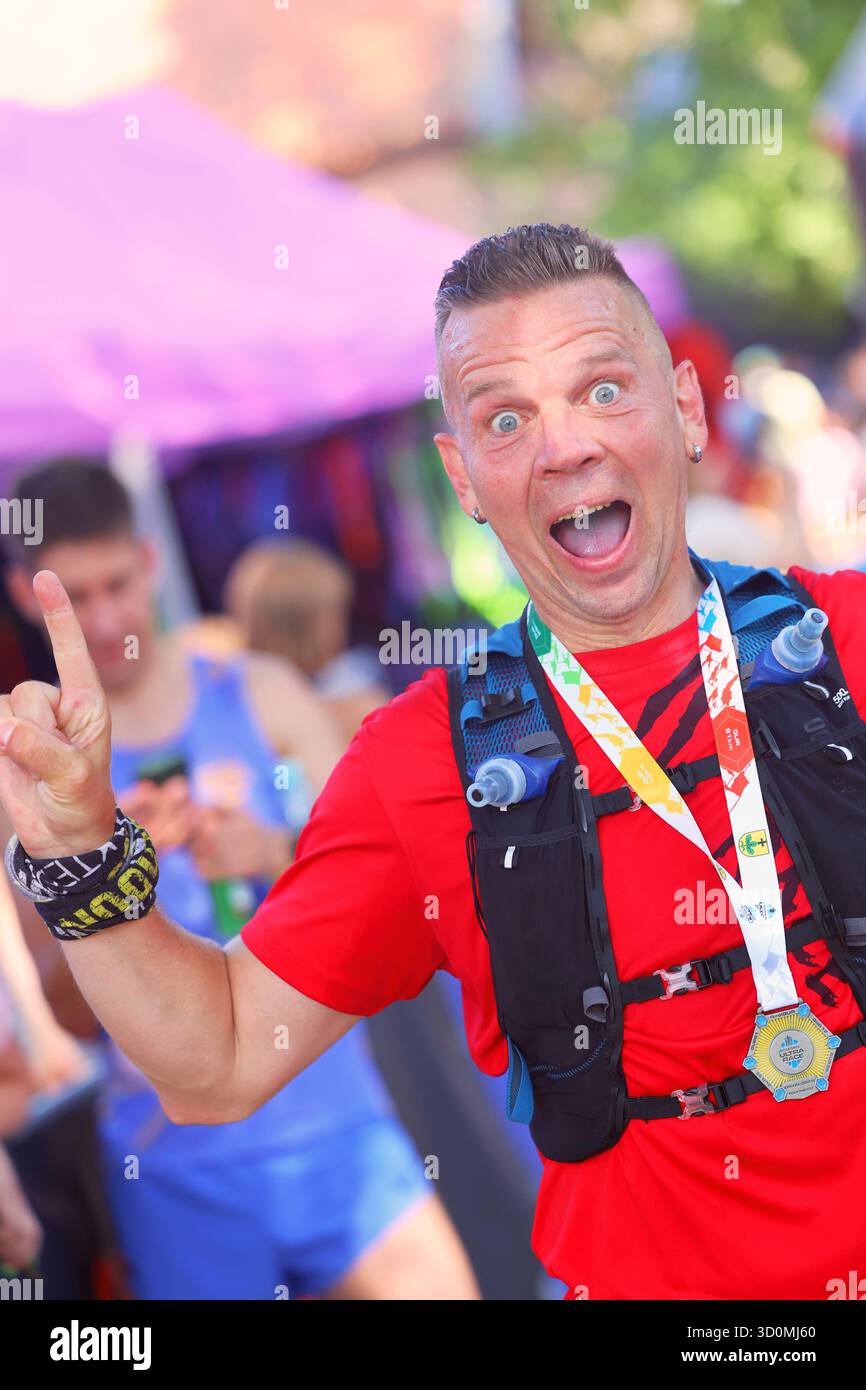 Der begeisterte Läufer feiert nach dem Ultra-Rennen mit hochgezogenem Finger Stockfoto