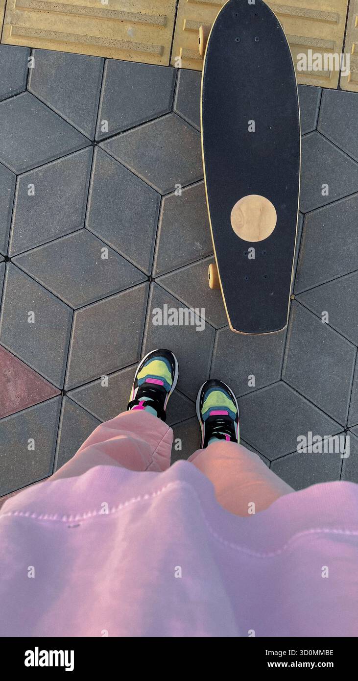Skateboarder auf dem Bürgersteig in der Stadt, mit Sneakers und lässigem Outfit Stockfoto