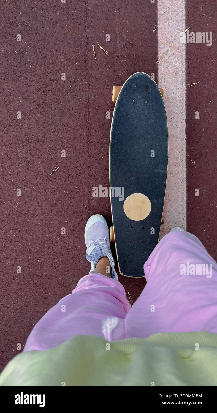 Skateboarder auf dem Bürgersteig in der Stadt, mit Sneakers und lässigem Outfit Stockfoto