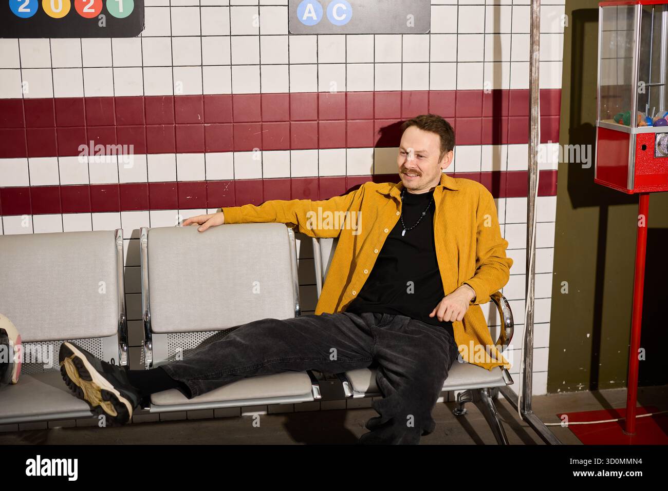 Mann, der sich in legeren Kleidern in einem Wartebereich im Retro-Stil entspannt Stockfoto