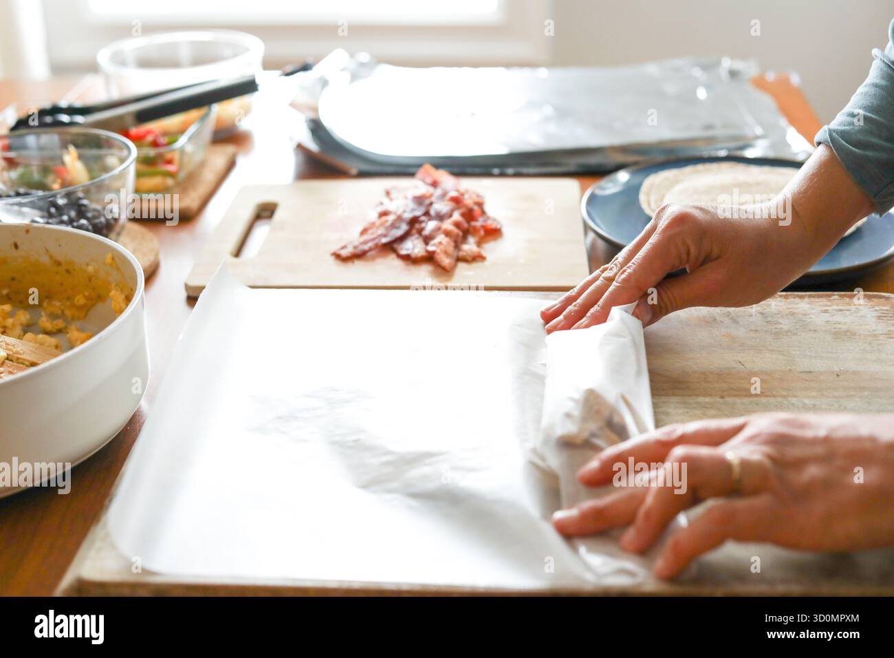 Frau rollt Frühstücks-Burrito in Wachspapier, um sie für den Gefrierschrank vorzubereiten Stockfoto