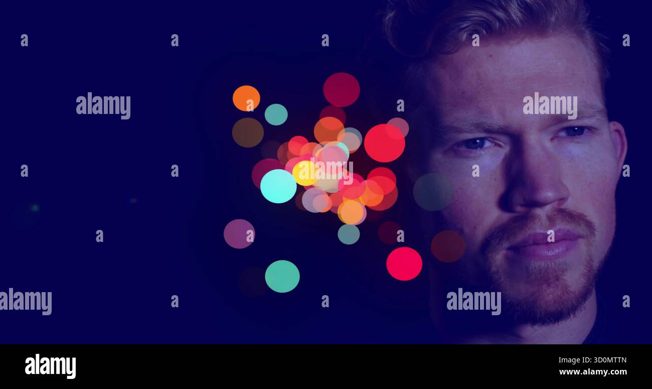 Guckender Mann mit dunklem Oberteil, der im Studio nachdenkt, mit bunten Bokeh-Lichtern, Kopierraum Stockfoto