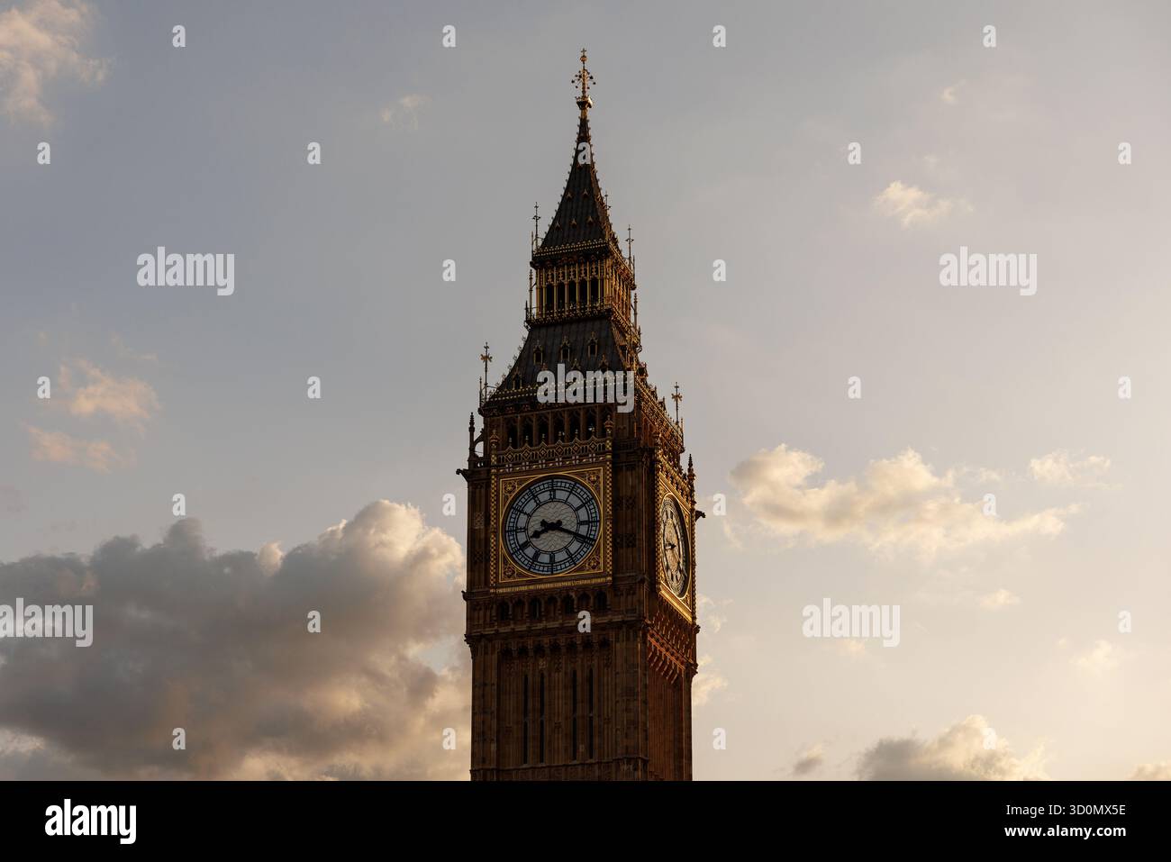 Blick aus der Nähe auf die berühmte Uhr und den kunstvollen Turm von Big Ben im warmen Abendlicht. Weiche Wolken umrahmen die Landmarke gegen den Himmel. Stockfoto