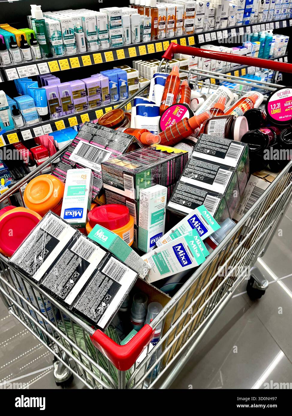 Der Einkaufswagen ist überfüllt mit Kosmetikprodukten in einem Drogerie-Laden, was Einkäufe und Überausgaben veranschaulicht - Smartphone-aufgenommenes Stockfoto