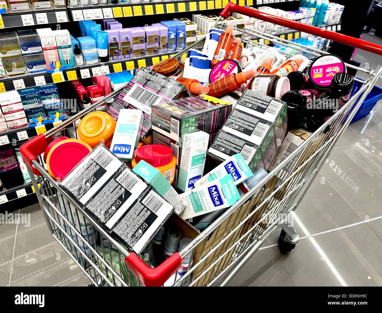 Einkaufswagen gefüllt mit verschiedenen Kosmetikprodukten in einem Drogerie-Laden Gang - Smartphone-aufgenommenes Stockfoto