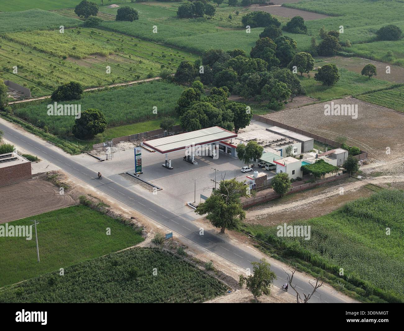 Aus der Vogelperspektive einer Tankstelle (Tankstelle) an einer Landstraße, umgeben von üppigen grünen Feldern und Bäumen in Punjab, Pakistan. Stockfoto