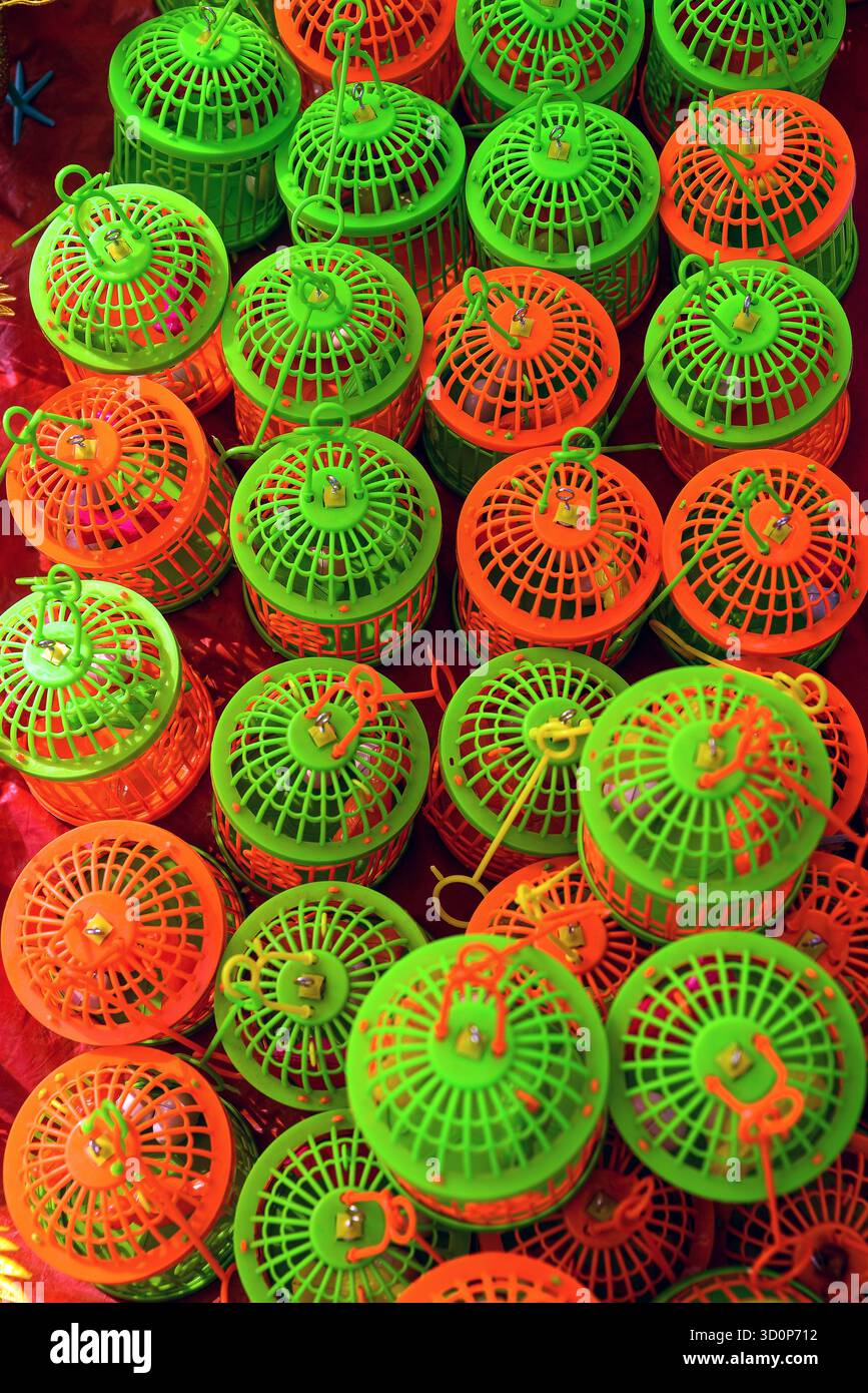 Leuchtend orange und grüne Kunststoff-Vogelkäfige in einem optisch auffälligen repetitiven Muster, geeignet für verschiedene künstlerische oder thematische Anwendungen. Stockfoto