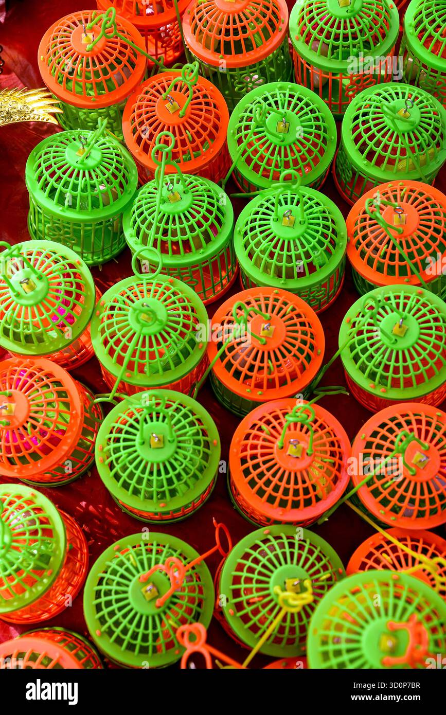 Leuchtend orange und grüne Kunststoff-Vogelkäfige in einem optisch auffälligen repetitiven Muster, geeignet für verschiedene künstlerische oder thematische Anwendungen. Stockfoto