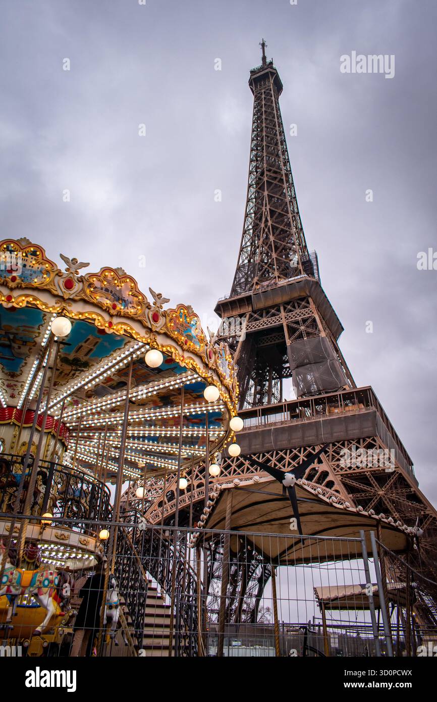 Der Eiffelturm in Paris, Frankreich, mit einem hell beleuchteten Karussell im Vordergrund. Stockfoto