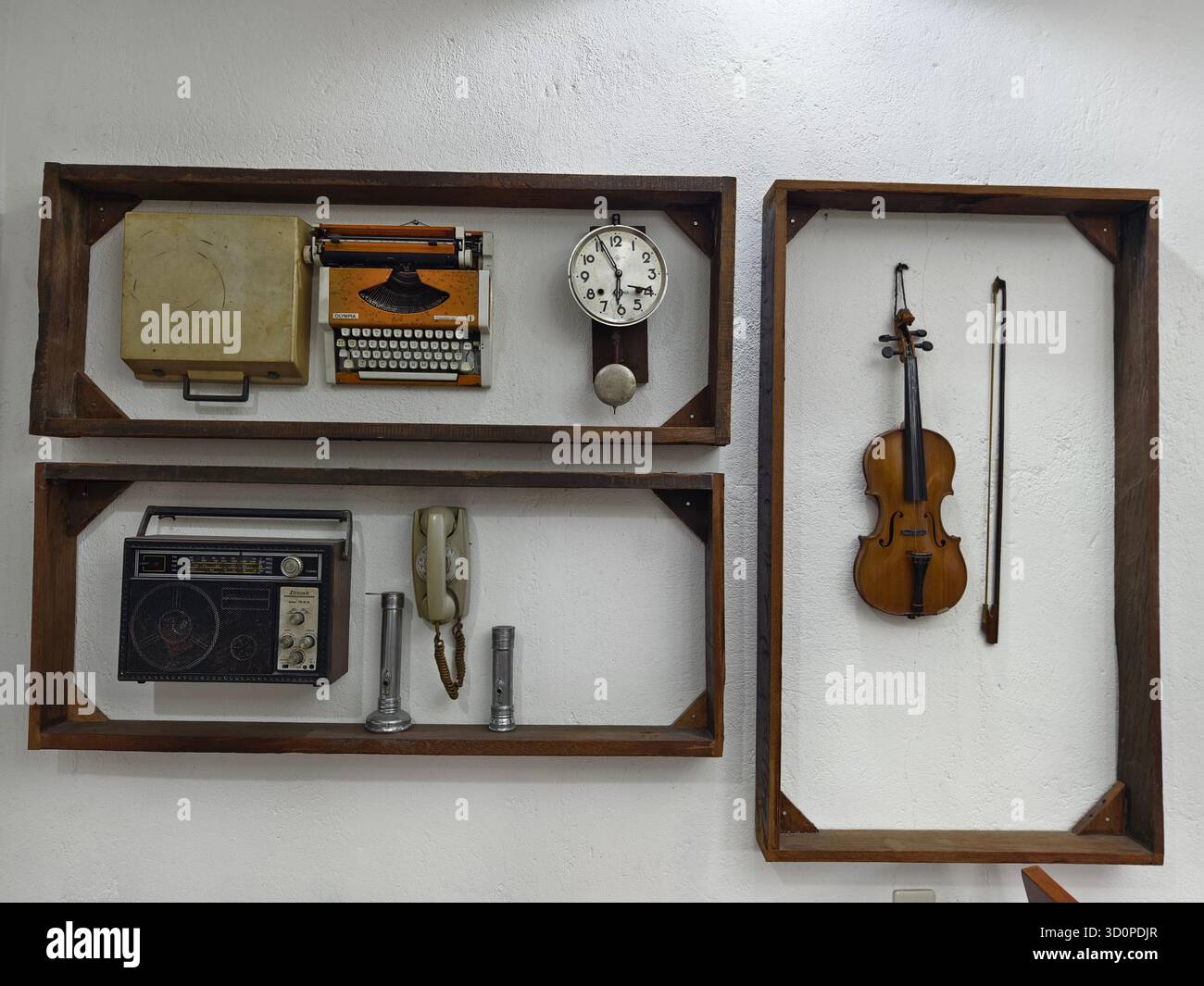 Eine Sammlung von Vintage-Artikeln, darunter eine Vintage-Schreibmaschine, eine alte Wandpendeluhr, ein Vintage-Radio, ein Drehtelefon, eine Violine und ein Bogen Stockfoto