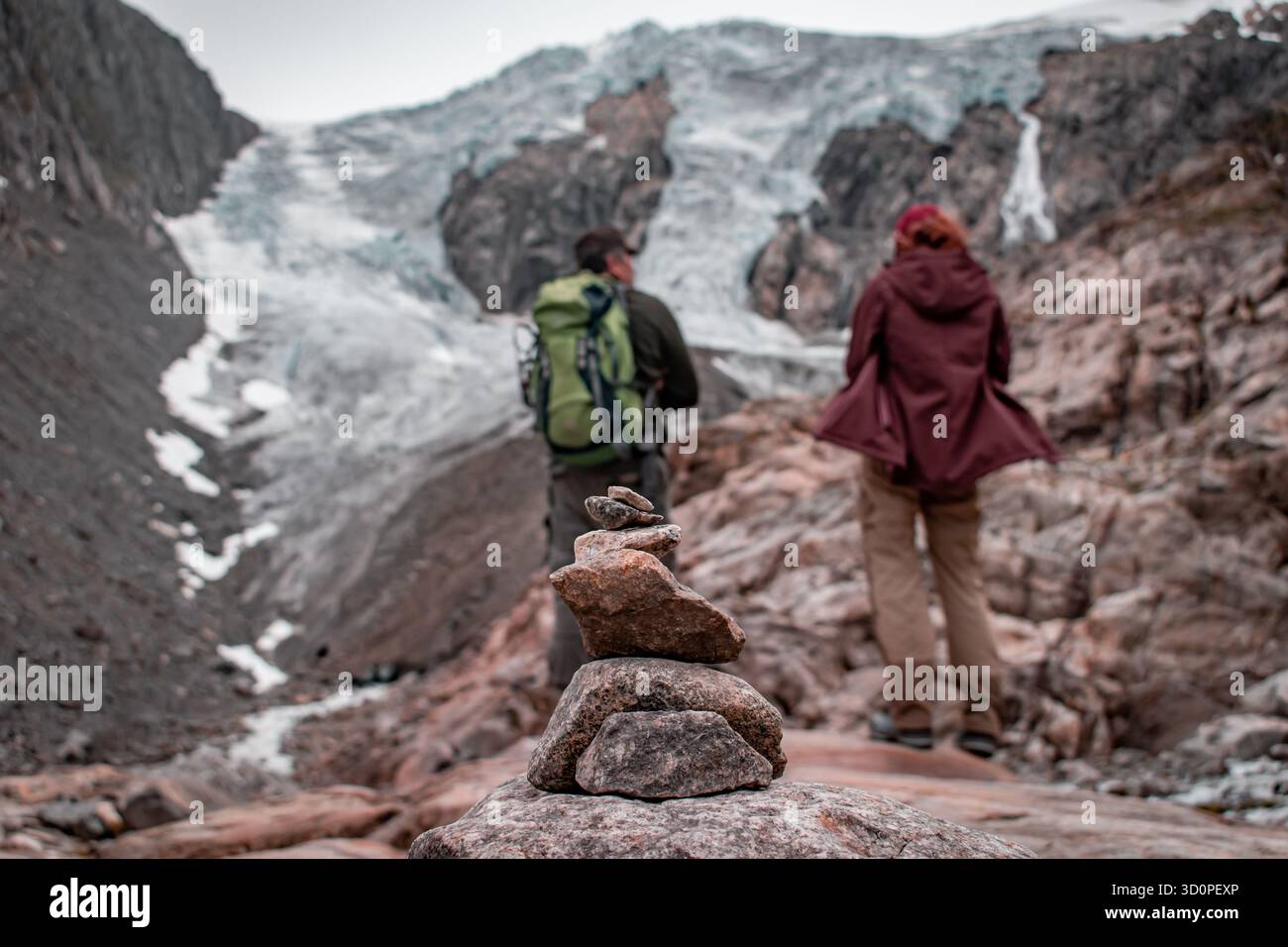 Ein Gletscher auf dem Berggipfel. Zwei Männer in Trekkingausrüstung sind auf den Gletscher geklettert. Stockfoto