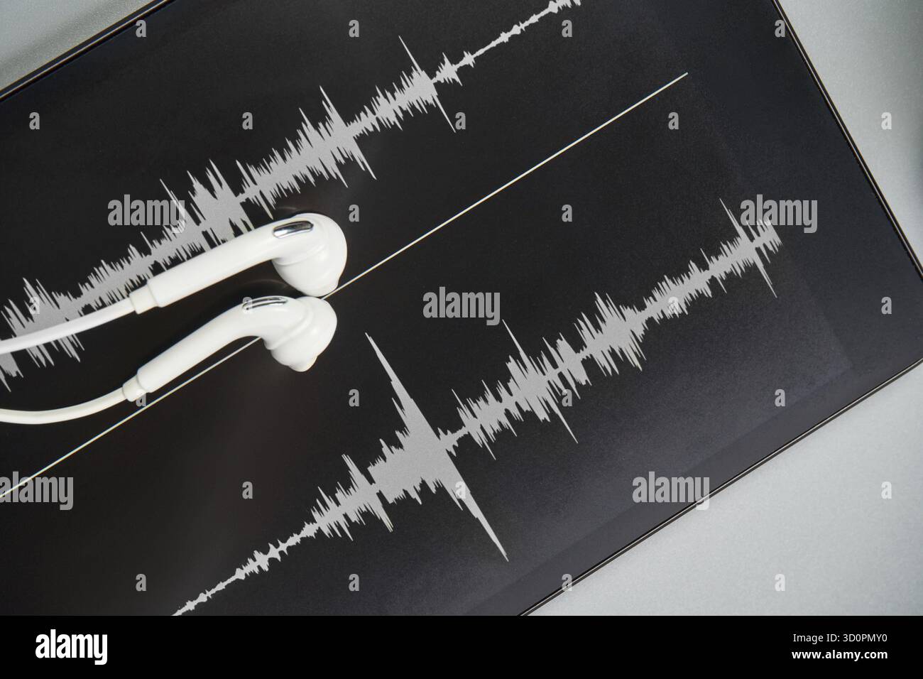 Podcast-Aufzeichnung. Ohrstöpsel und Soundtrack am Tablet. Graues Schwarzweiß. Hörbuch und Podcasting. Audiotechnologie. Hausschulunterricht. Episode bearbeiten Stockfoto