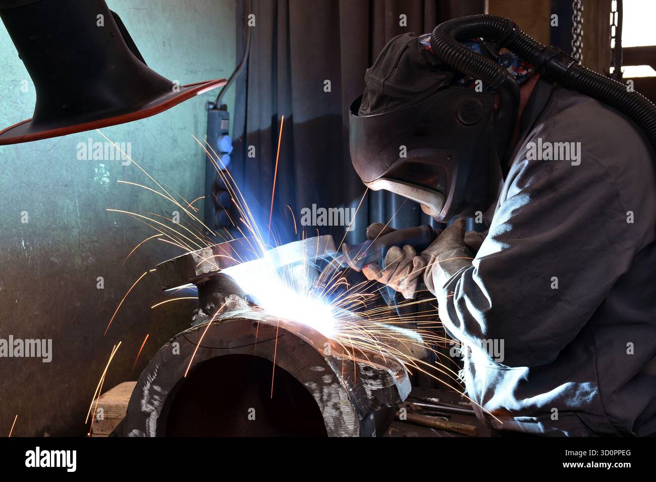 Schweißer in Schutzkleidung am Arbeitsplatz in einem Industrieunternehmen im Stahlbau - Nahaufnahme Stockfoto