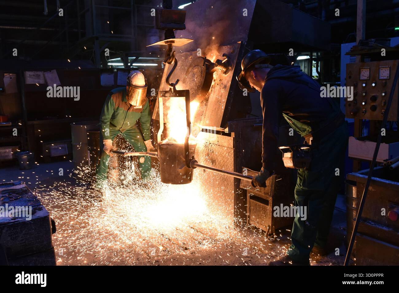Gruppe von Arbeitern in Sicherheitskleidung in einer Eisengießerei - Befüllen der Gießpfanne mit heißem Metall - industrielle Produktion - Nahaufnahme Stockfoto