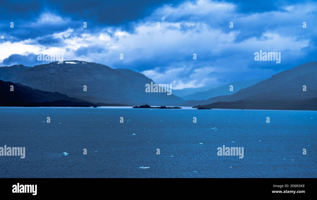 Die ruhige Szene fängt die Schönheit der Natur mit einem ruhigen See und entfernten Bergketten ein Stockfoto