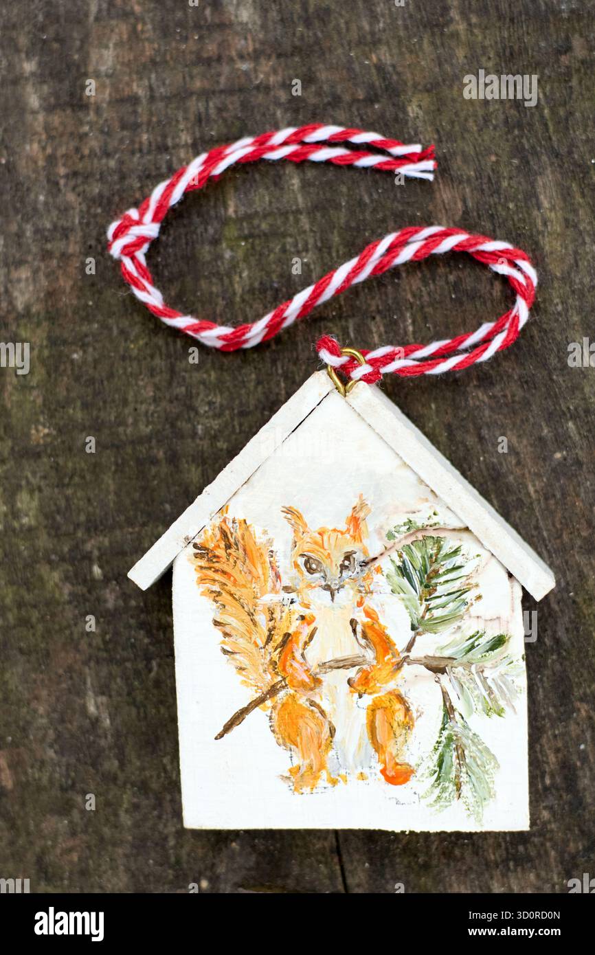 Bezauberndes Eichhörnchen-Haus-Ornament auf einer rustikalen Holzoberfläche, die einen Hauch von Charme und Natur-inspirierter Schönheit in die Urlaubseinrichtung einfügt. Stockfoto