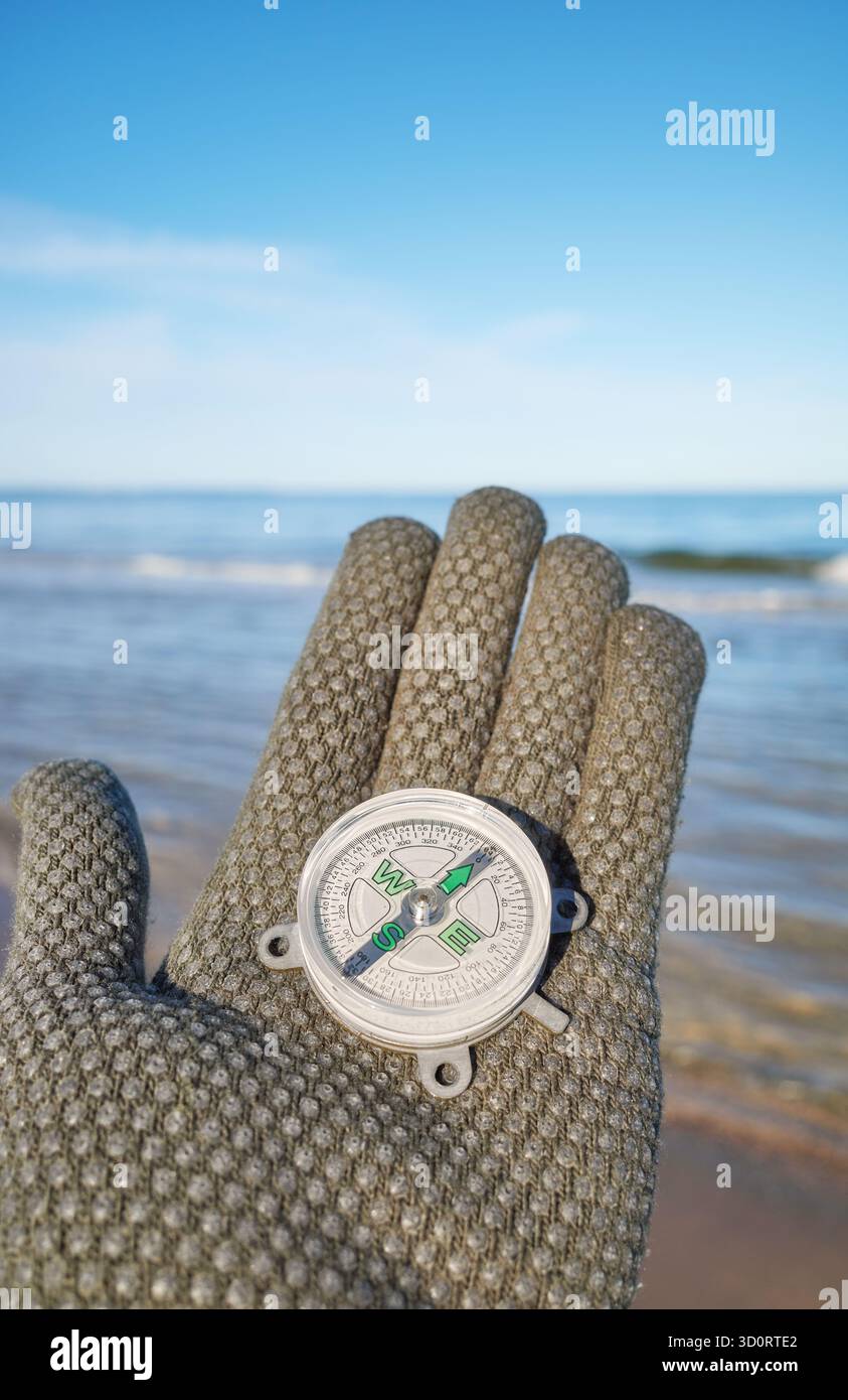 Kompass in einer Hand mit Meer im Hintergrund, selektiver Fokus Stockfoto