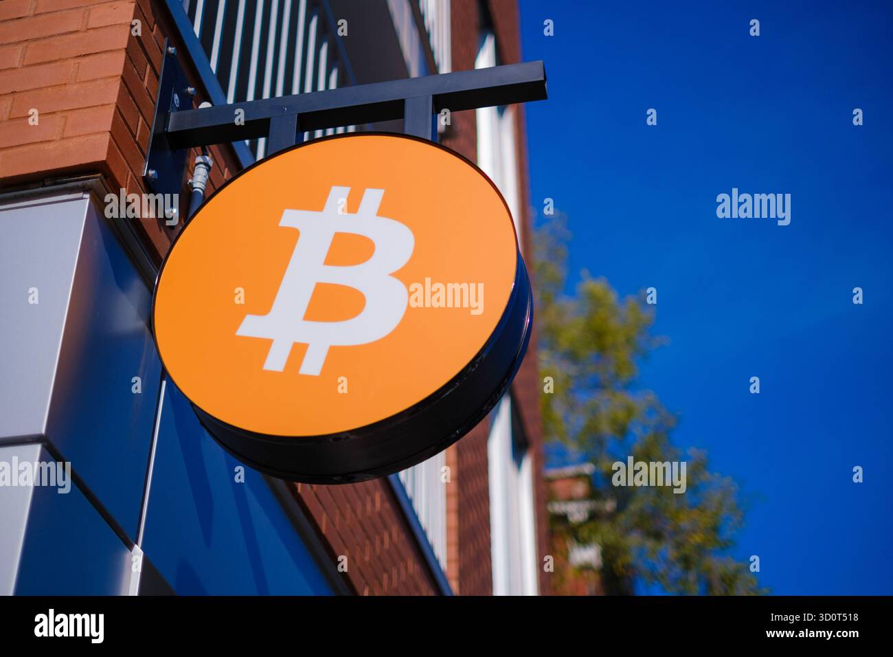 Shop-Schild mit dem Bitcoin-Kryptowährung-Logo und einem leuchtend blauen Himmel im Hintergrund Stockfoto