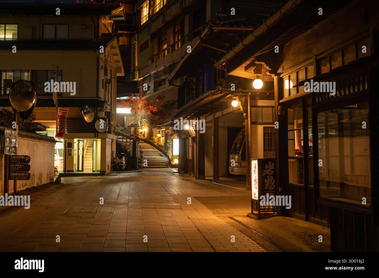 Nur redaktionelle Verwendung. Traditionelle japanische Straße bei Nacht mit warmen Lichtern und Ryokan-Schildern Stockfoto