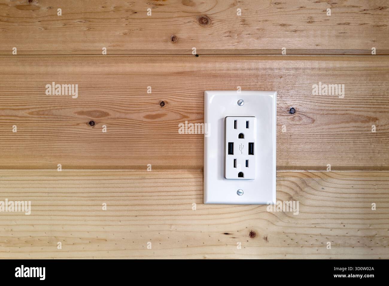 Eine zweifache 110-Volt-Steckdose mit USB-Anschlüssen an einer holzgetäfelten Wand Stockfoto