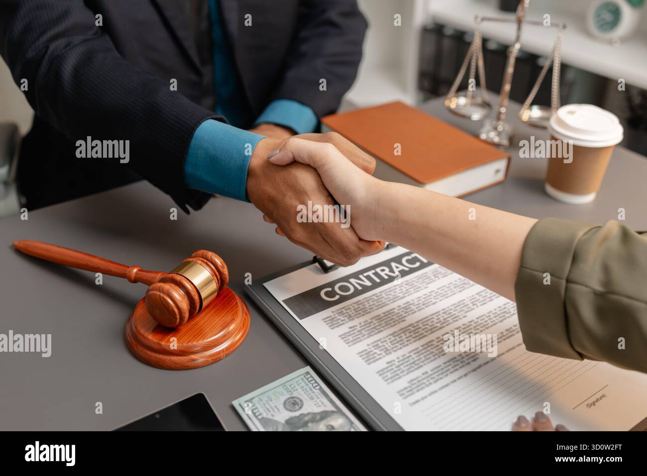 Ein geschäftlicher Handschlag zwischen einem Anwalt und einem Klienten, nachdem er einen Vertrag in einem modernen Büro unterzeichnet hat. Das Abkommen, der Hammer und das Geld auf dem Tisch SY Stockfoto