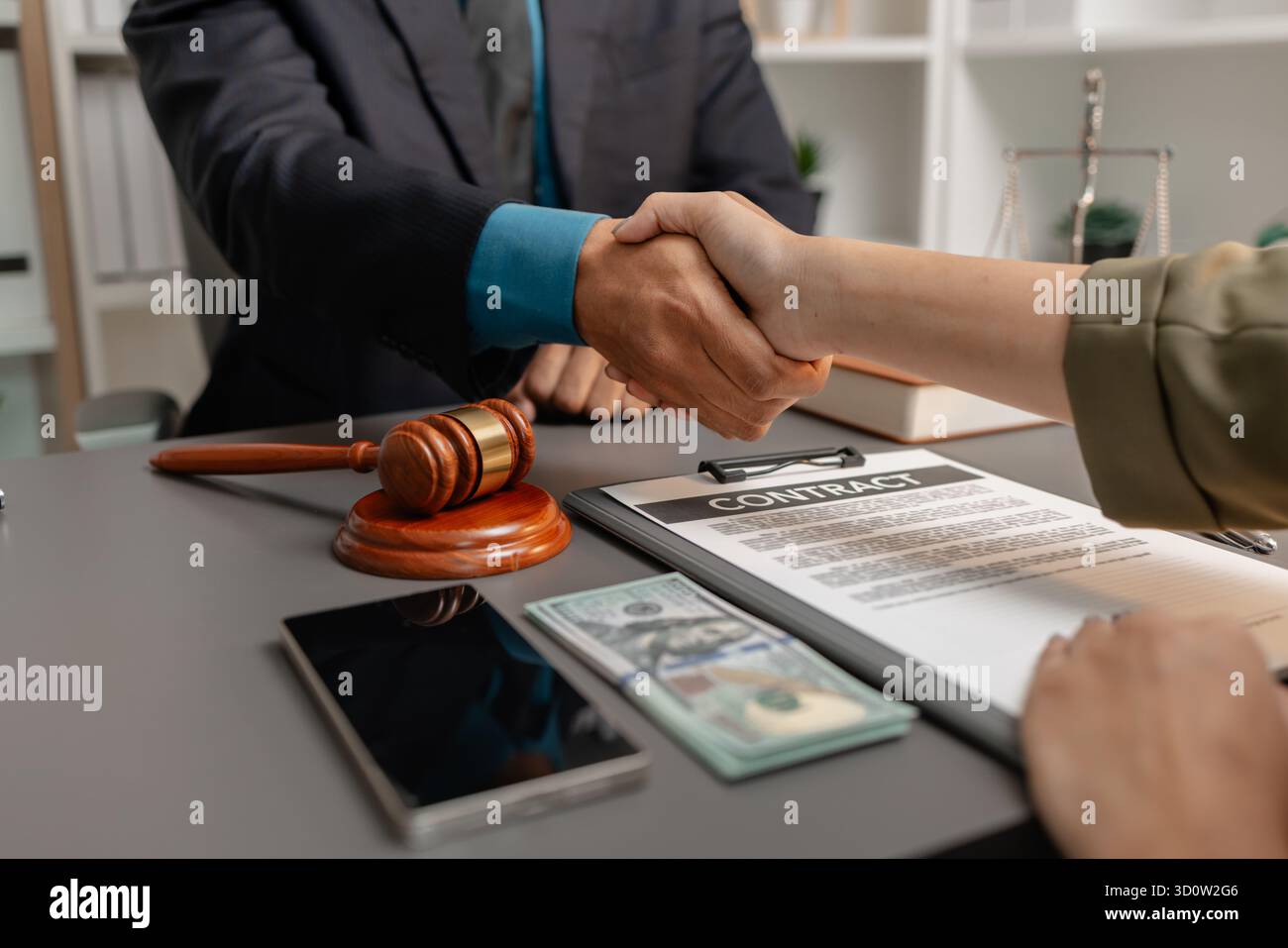 Ein geschäftlicher Handschlag zwischen einem Anwalt und einem Klienten, nachdem er einen Vertrag in einem modernen Büro unterzeichnet hat. Das Abkommen, der Hammer und das Geld auf dem Tisch SY Stockfoto