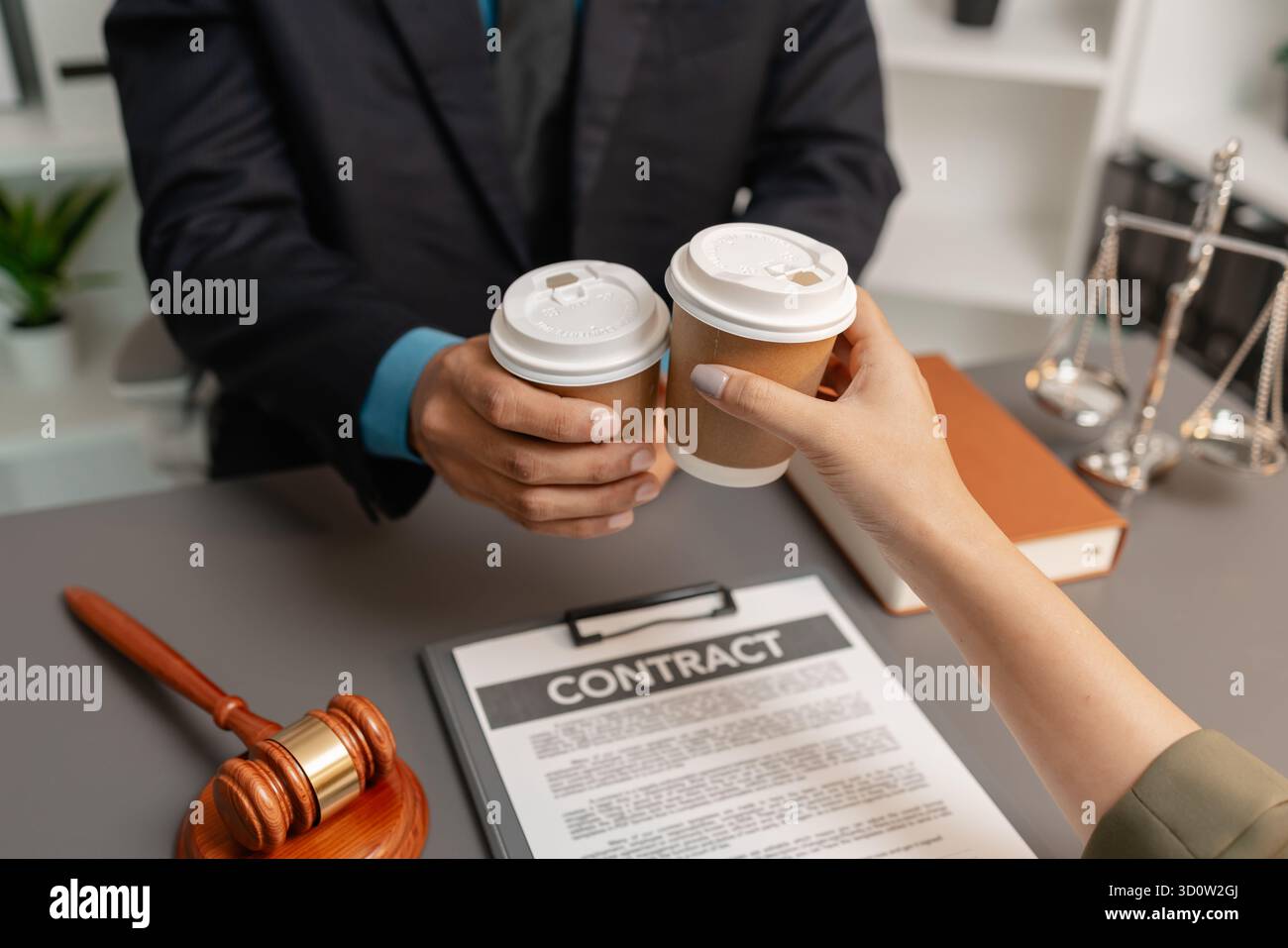 Ein Anwalt und ein Kunde feiern den erfolgreichen Abschluss einer Rechtsvereinbarung mit einem Kaffeetoast im Büro, der Vertrauen, Partnerschaft und symbolisiert Stockfoto