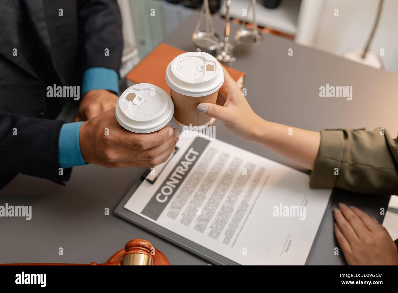 Ein Anwalt und ein Kunde feiern den erfolgreichen Abschluss einer Rechtsvereinbarung mit einem Kaffeetoast im Büro, der Vertrauen, Partnerschaft und symbolisiert Stockfoto