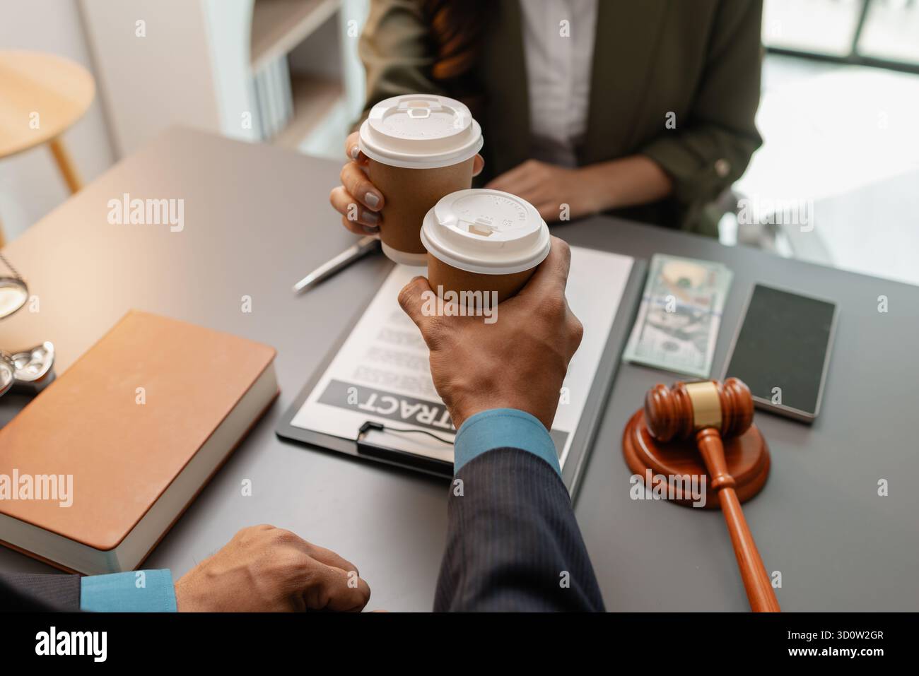 Ein Anwalt und ein Kunde feiern den erfolgreichen Abschluss einer Rechtsvereinbarung mit einem Kaffeetoast im Büro, der Vertrauen, Partnerschaft und symbolisiert Stockfoto