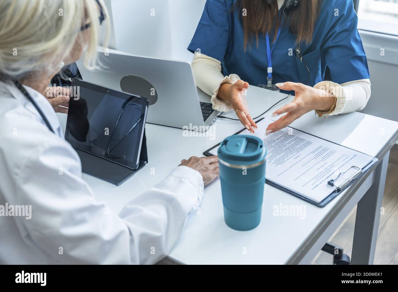 Medizinisches Fachpersonal diskutiert medizinische Informationen während einer Konsultation in einem Büro mit einem Laptop, Tablet und Dokumenten, die moderne m repräsentieren Stockfoto