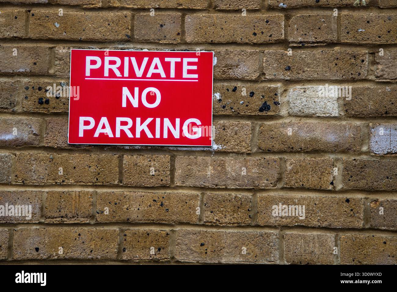 Nahaufnahme eines roten „Private No Parking“-Schilds an einer Mauer, das Fahrer vor dem Parken warnt, Konzept der Einschränkung und Zugang zum Grundstück. Stockfoto