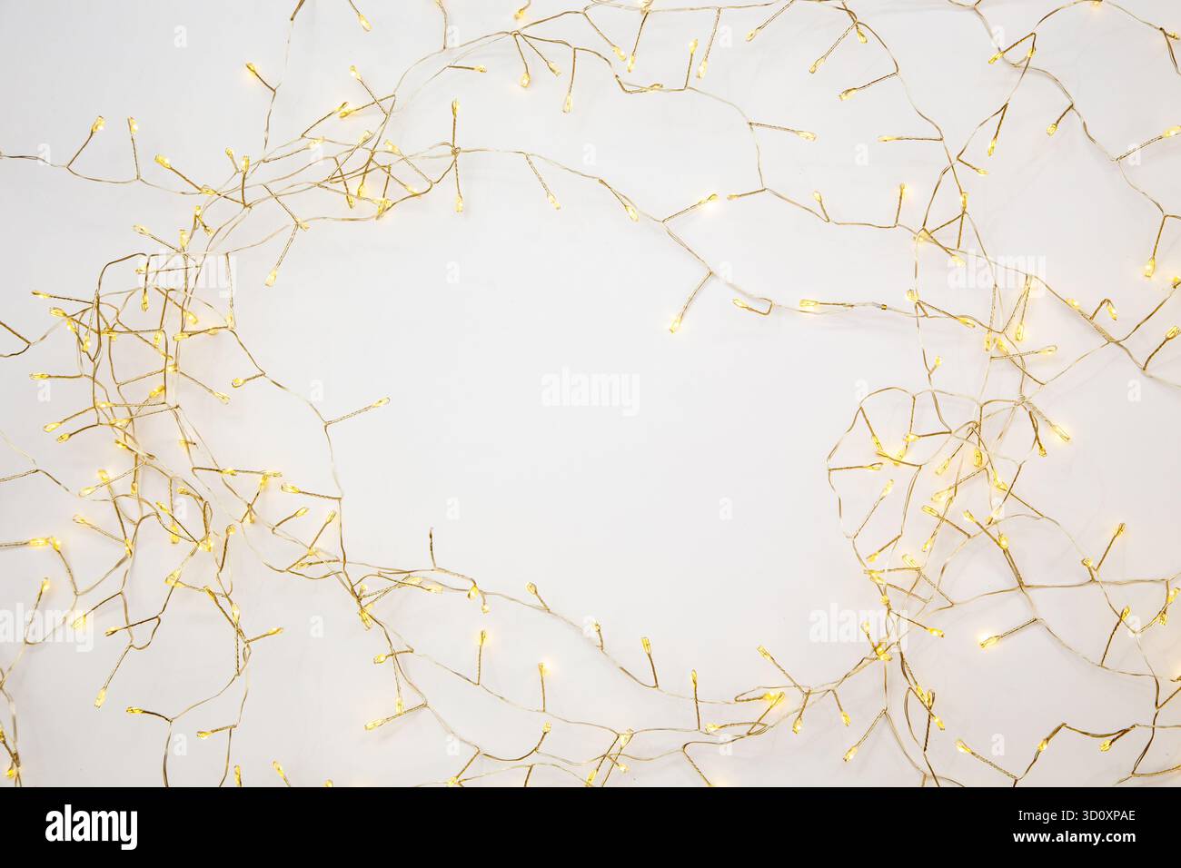 Goldene warme Lichter, die sanft weißen Hintergrund beleuchten. Gemütliche Hygge-Atmosphäre, perfekt für Wohnkultur, Komfort, Entspannung und Lifestyle-Branding Stockfoto